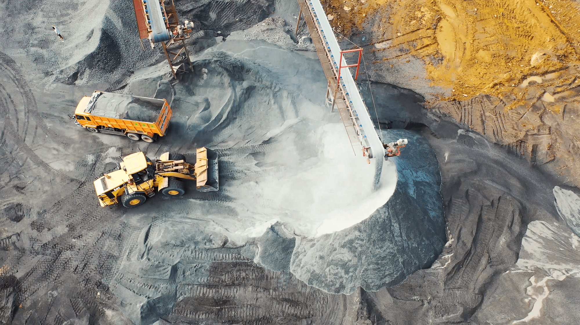Drone shot of conveyors and trucks at a mine site