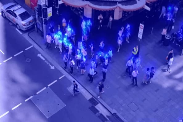 A heatmap of pedestrians gathered on a sidewalk, with clusters of people more brightly coloured than the rest of the scene.