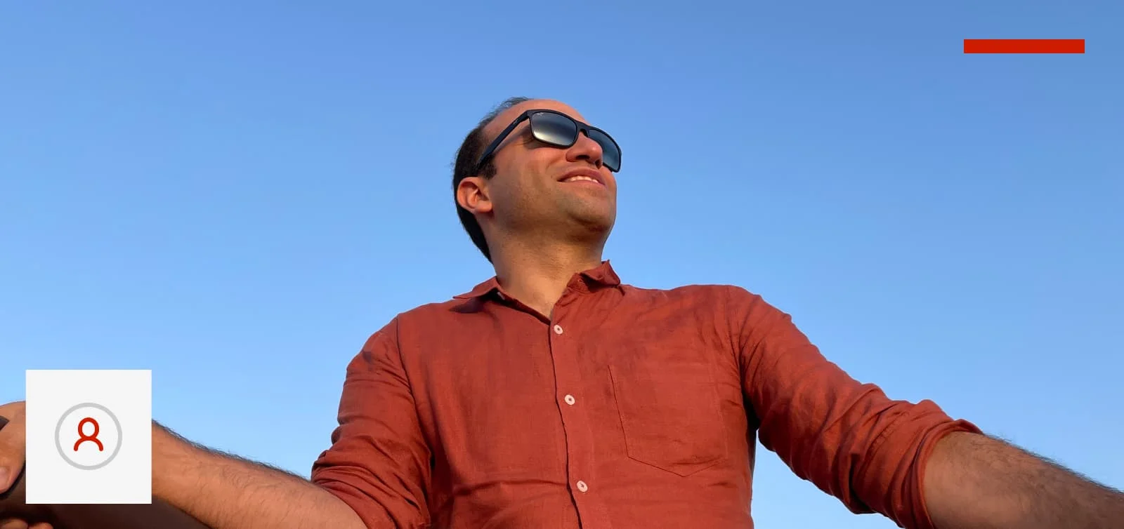 Shahab Ensafi, Unleash Live's Head of AI in an orange shirt and sunglasses on a sky blue backdrop